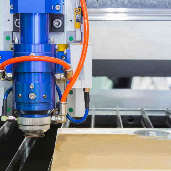 CNC machine cutting a piece of clear acrylic with brown paper on back.