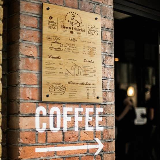 Custom Bamboo Sign Engraved With Cafe Logo And Menu Mounted Onto Brick Wall Outdoors Via 4 Gold Standoffs Above Coffee Text