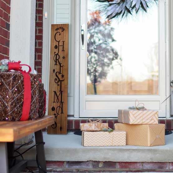 Bamboo Sign Laser Engraved With Merry Christmas Text And Ornament Art Leaning Beside Front Porch Door Near Wrapped Presents