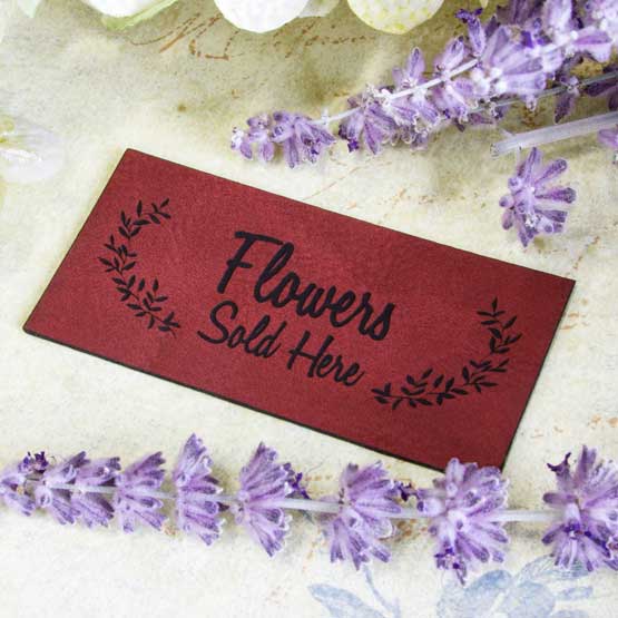 Rose And Black Faux Leather Label Engraved With Wheat Art And Flowers Sold Here Text On Countertop With Purple Flowers