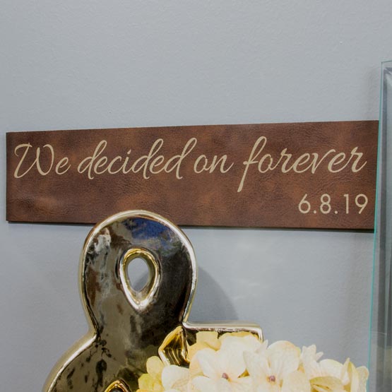 Rustic And Gold Faux Leather Sign Engraved With Cursive We Decided On Forever Text And Date On Wall Above Flowers And Decor