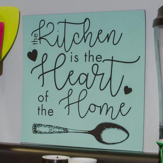 Teal And Black Faux Leather Sign Engraved With Kitchen Is The Heart Of The Home Text And Spoon Art On Counter With Blender