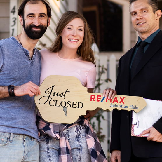 Realtor Posing Outdoors With Happy Couple Holding House Key Shaped Maple Wood Sign Printed With Just Closed Message And Logo