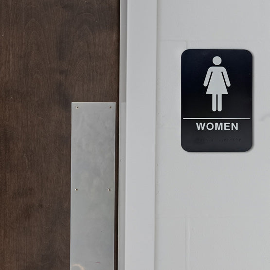 Custom Black And White Plastic Sign With Women Icon And Text And Braille Mounted On Wall Next To Wood Door