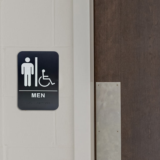 Black And White Plastic Sign With Men And Wheelchair Icons Above Men Text With Braille Mounted On Wall Beside Wood Door