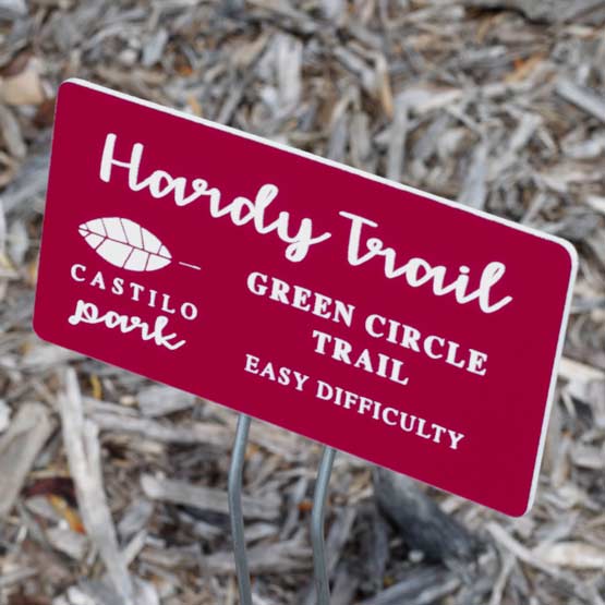 Custom Red Plastic Garden Sign Laser Engraved With Hardy Trail And Park Details Text Standing In Mulch Via Metal Stand