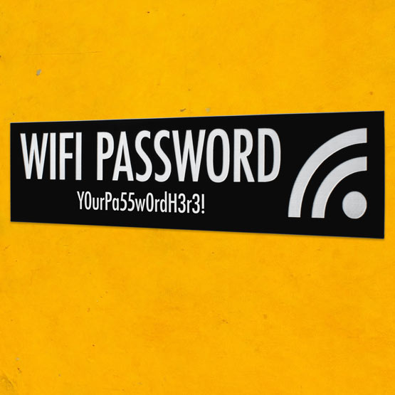 Custom Black And White Plastic WiFi Sign Engraved With WiFi Password Details And WiFi Icon Mounted Onto Yellow Wall