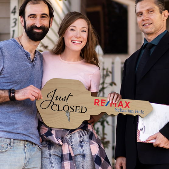 Realtor Posing Outdoors With Happy Couple Holding House Key Shaped Red Alder Sign Printed With Just Closed Message And Logo