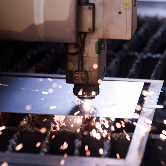 CNC machine cutting stainiless steel metal with sparks in an industrial setting