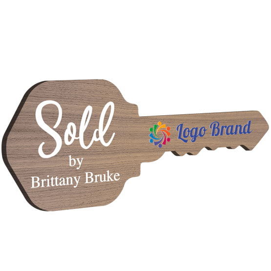 House Key Shaped Walnut Wood Sign Color Printed With Sold By Message And Sample Name And Logo Against White Background