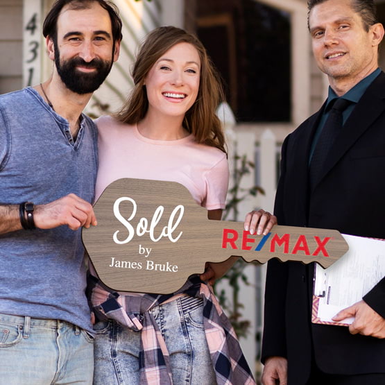 Realtor Posing Outdoors With Happy Couple Holding House Key Shaped Walnut Wood Sign Printed With Sold By Message And Logo