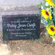 Order 832756 Review Image. In Loving Memory Headstone on the ground by yellow flowers.
