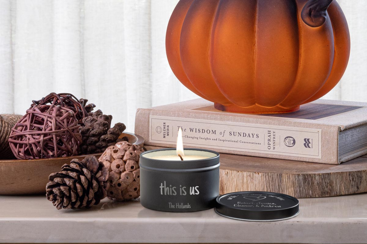A customized 8oz tin candle sitting next to fall decorations. The scent is pumpkin spice.