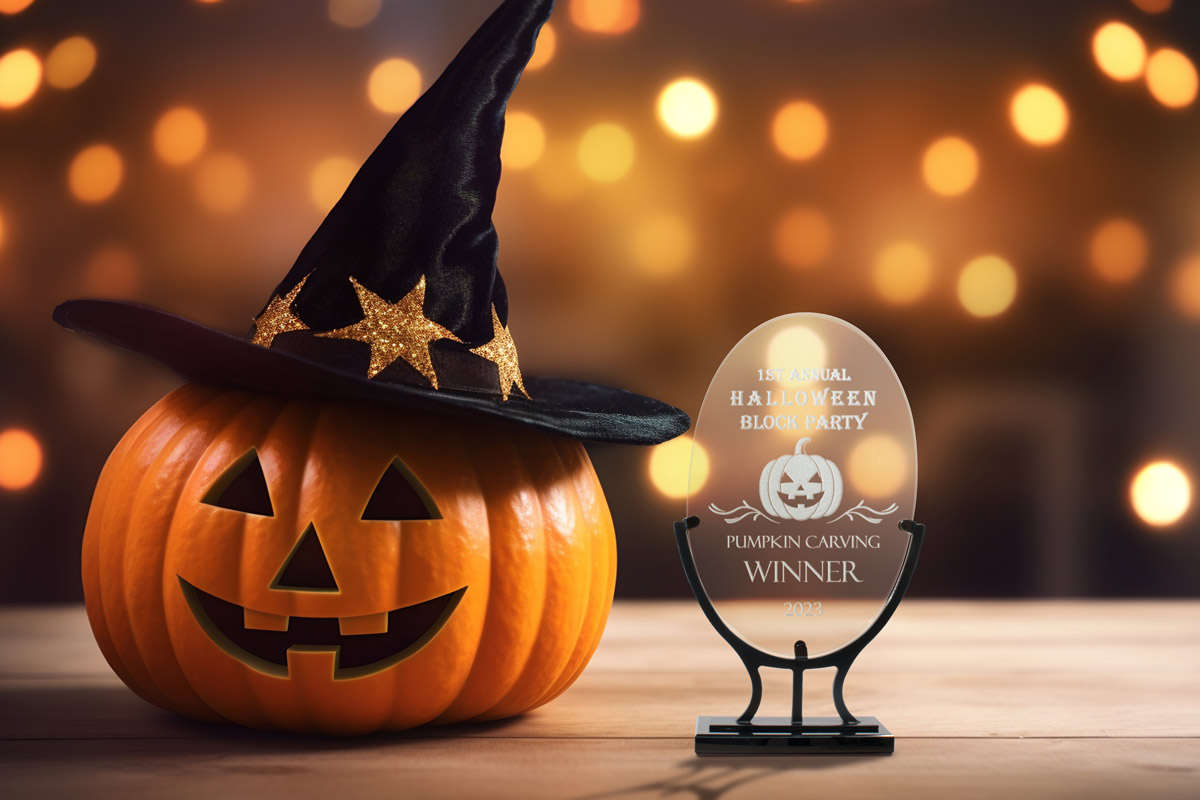 An oval glass award on an iron stand with a custom design for the winner of a pumpkin craving contest engraved on the front.