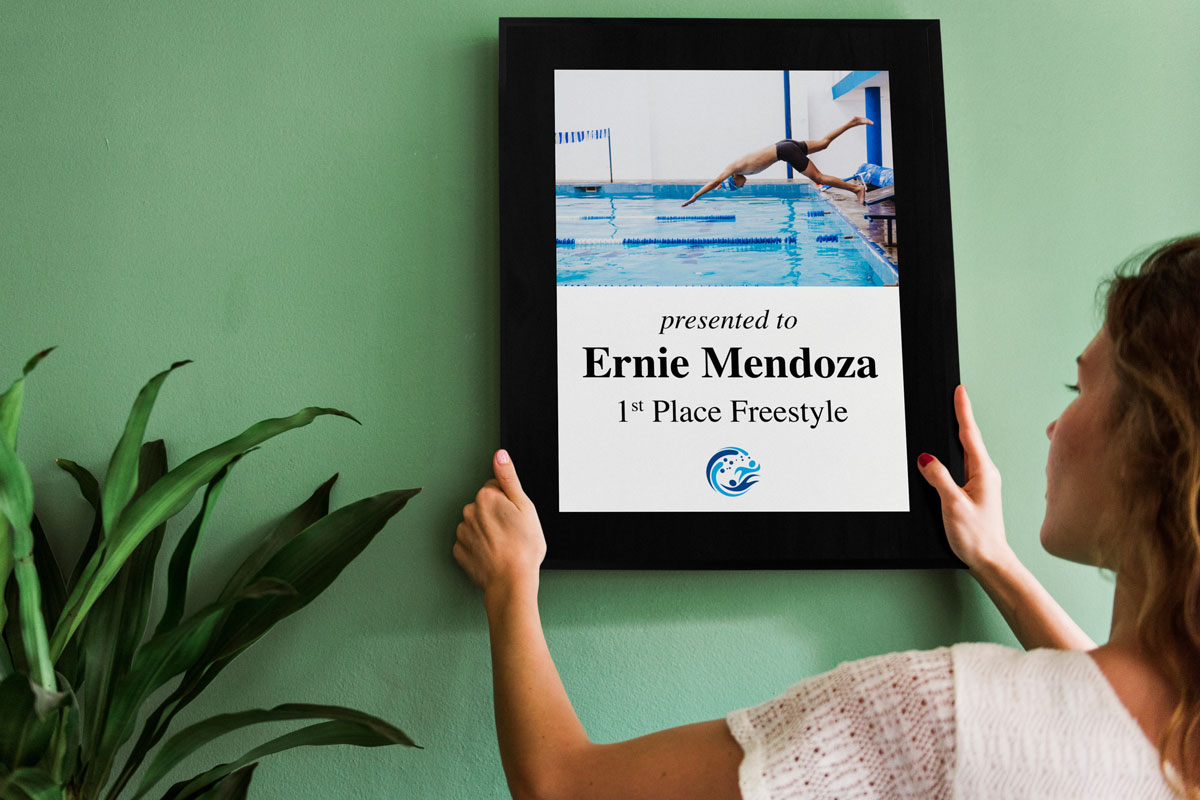 Young woman hanging a custom aluminum plaque celebrating a swimming achievement