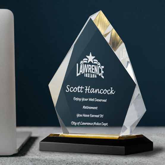 Fully customizable diamond acrylic award on a gold mirrored base, sitting on a desk to display an achievement or award.