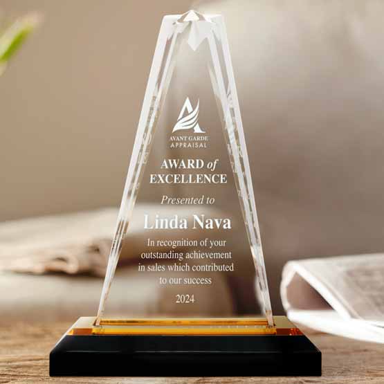 Custom Engraved Gold Acrylic Star Tower Trophy for Linda Nava on coffee table near newspaper.