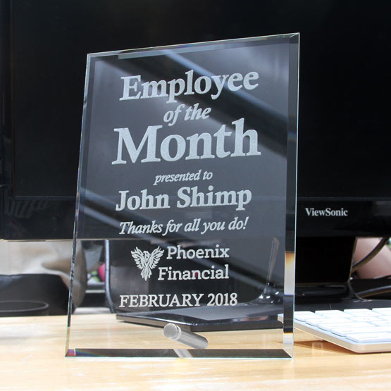 Custom Glass Economy pre-designed award with silver pin sitting on a desk with a laser engraved award displayed