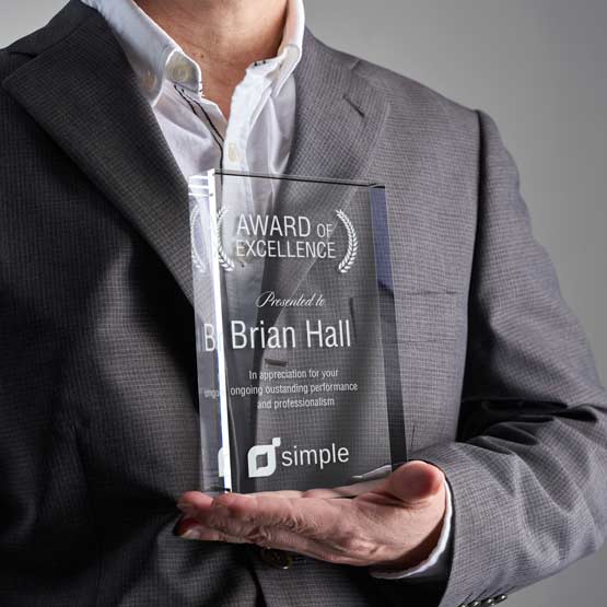 Man Holding Custom Engraved Standing Glass Award Against His Chest