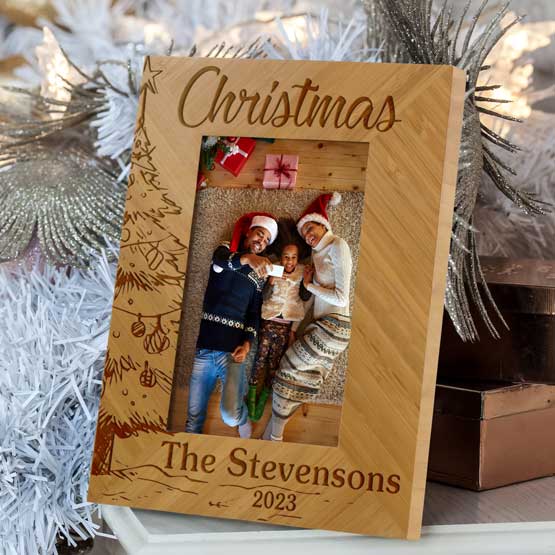 Customizable Christmas Tree Family Photo Frame, laser engraved into eco-friendly bamboo wood. Displayed on holiday table.