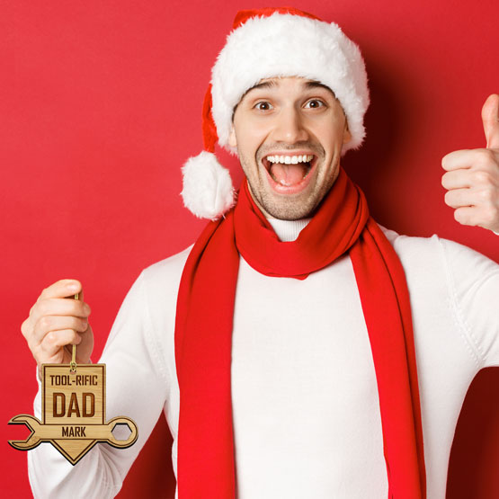 Man In Santa Hat Giving Thumbs Up And Holding Custom Bamboo Ornament With Tool-rific Dad Text And Tool Art
