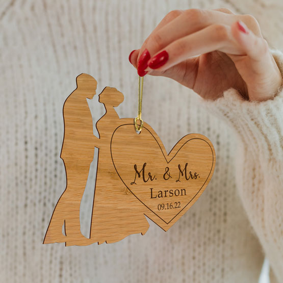 Personalized Bamboo Married couple ornament being held by the gold string that is include with purchase, makes a great gift