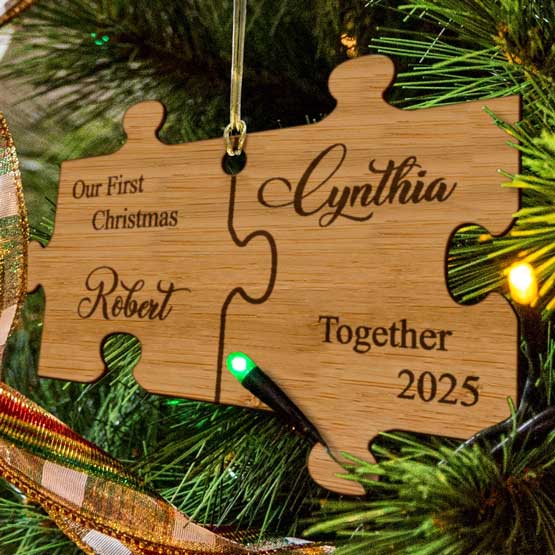 Customizable First Christmas Together ornament in the shape of a puzzle piece hanging by a golden string in a Christmas Tree.