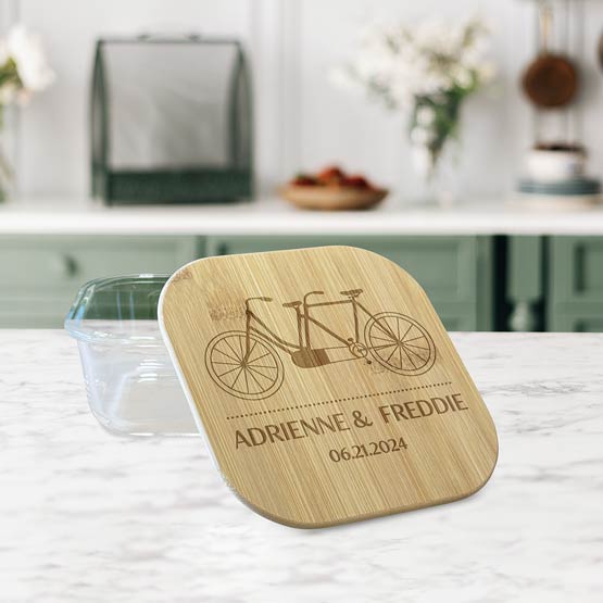 Square Glass Baking Dish With Bamboo Lid Featuring Tandem Bike And Couple Names Sitting On White Marble Kitchen Counter