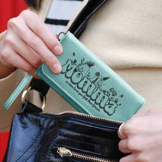 Custom Wrist Wallet for Mom engraved with Momma and a cute saying. The woman is placing the teal wallet in her bag.