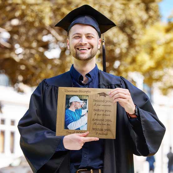 Personalized Class Of red alder message frame, being held by a graduating student. Engraved with their name, school, and year