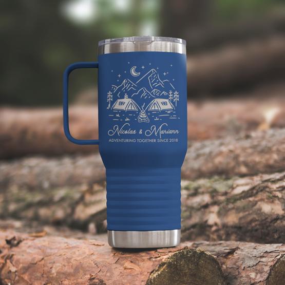 Custom Engraved 20 oz Blue Tumbler on a wooden log with a sample engraving for Nicolas & Mariann