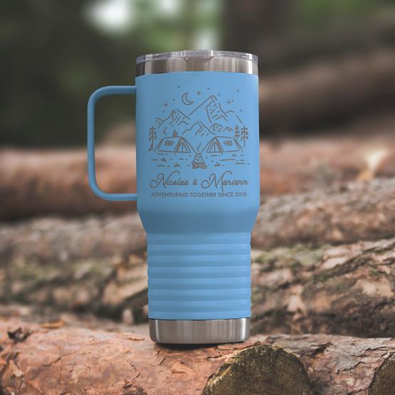 Custom Engraved 20 oz Light Blue Tumbler on a wooden log with a sample engraving for Nicolas & Mariann