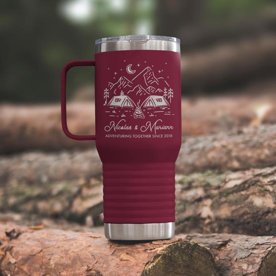 Custom Engraved 20 oz Maroon Tumbler on a wooden log with a sample engraving for Nicolas & Mariann