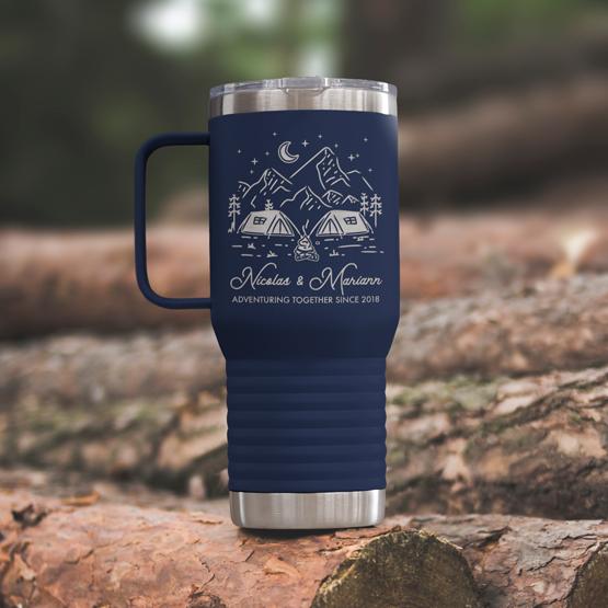 Custom Engraved 20 oz Navy Tumbler on a wooden log with a sample engraving for Nicolas & Mariann