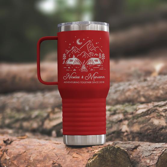 Custom Engraved 20 oz Red Tumbler on a wooden log with a sample engraving for Nicolas & Mariann