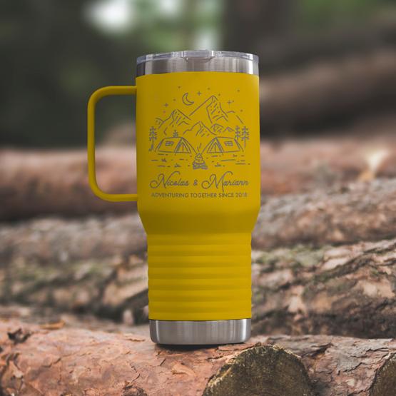 Custom Engraved 20 oz Yellow Tumbler on a wooden log with a sample engraving for Nicolas & Mariann