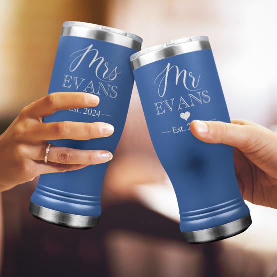 Two Custom Engraved Blue Beer Pilsner Tumblers held by woman and man with sample engraving for Mr & Mrs Evans