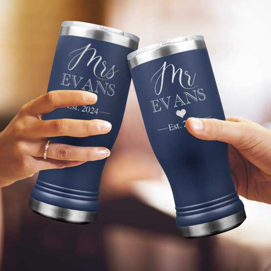 Two Custom Engraved Navy Beer Pilsner Tumblers held by woman and man with sample engraving for Mr & Mrs Evans