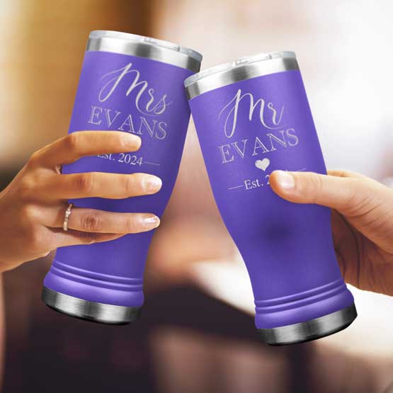 Two Custom Engraved Purple Beer Pilsner Tumblers held by woman and man with sample engraving for Mr & Mrs Evans