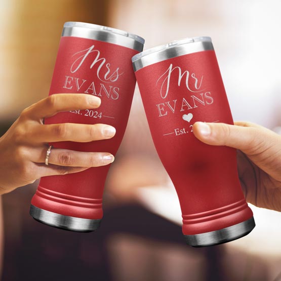 Two Custom Engraved Red Beer Pilsner Tumblers held by woman and man with sample engraving for Mr & Mrs Evans