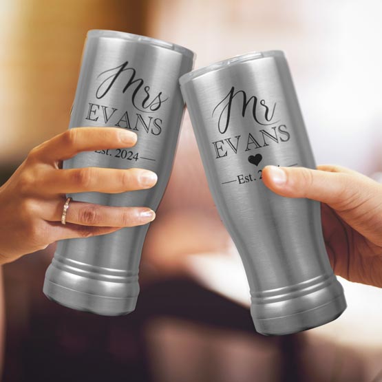 Two Custom Engraved Silver Beer Pilsner Tumblers held by woman and man with sample engraving for Mr & Mrs Evans