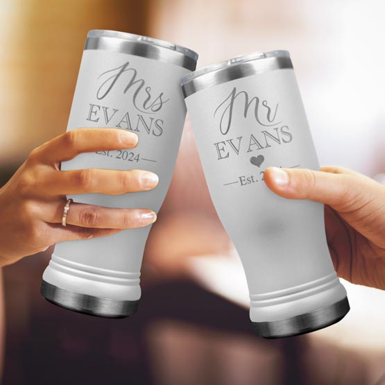 Two Custom Engraved White Beer Pilsner Tumblers held by woman and man with sample engraving for Mr & Mrs Evans