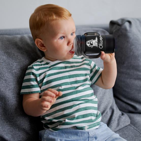 Custom Engraved 10 oz Black Sippy Cup held by toddler with a sample engraving for Oliver