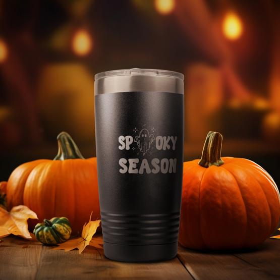 Pre-designed Spooky Season 20 oz Tumbler. Sitting on an outside table surrounded pumpkins. Design laser engraved on the front