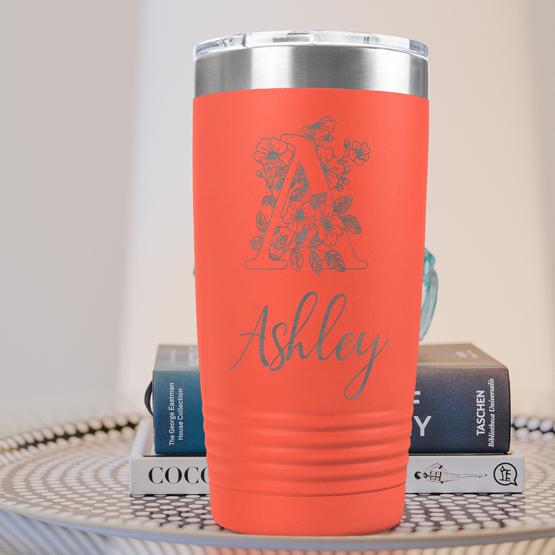 Custom Engraved 20 oz Coral Tumbler on a side table with books