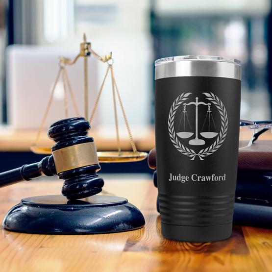 Custom Black Scales of Justice Tumbler for Judge Crawford sitting on table near gavel, scales of justice, books, and glasses.