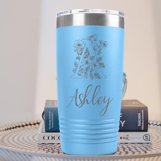 Custom Engraved 20 oz Light Blue Tumbler on a side table with books