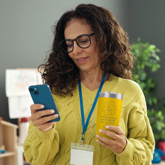 Woman holding a personalized Piece of My Story yellow tumbler that has her name engraved at the top of the tumbler.