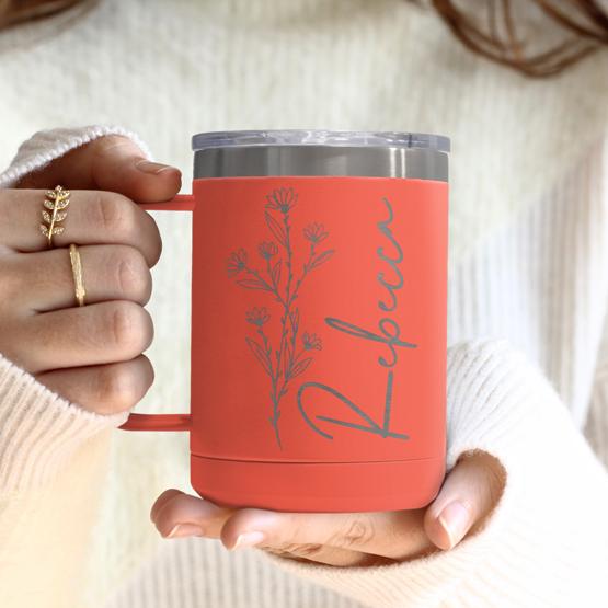 Custom Engraved 15 oz Coral Tumbler Mug being held by a woman with a sample engraving for Rebecca