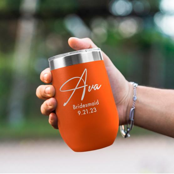 Custom Engraved 16 oz Orange Wine Tumbler held by woman with the engraving for Ava.